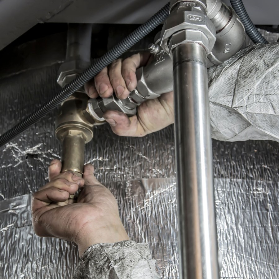 Plumber fixing pipe fittings under a sink
