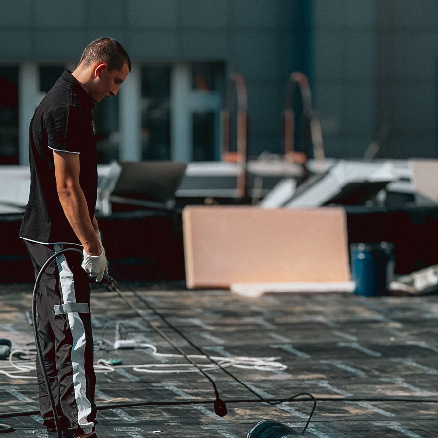 Worker applying waterproof membrane on a flat rooftop